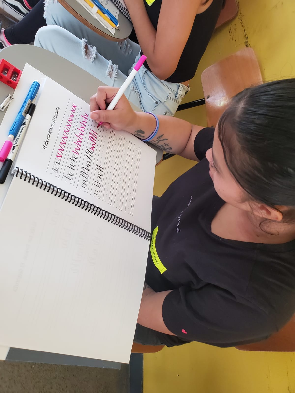 Mujer escribiendo en un cuaderno, siguiendo trazos preescritos