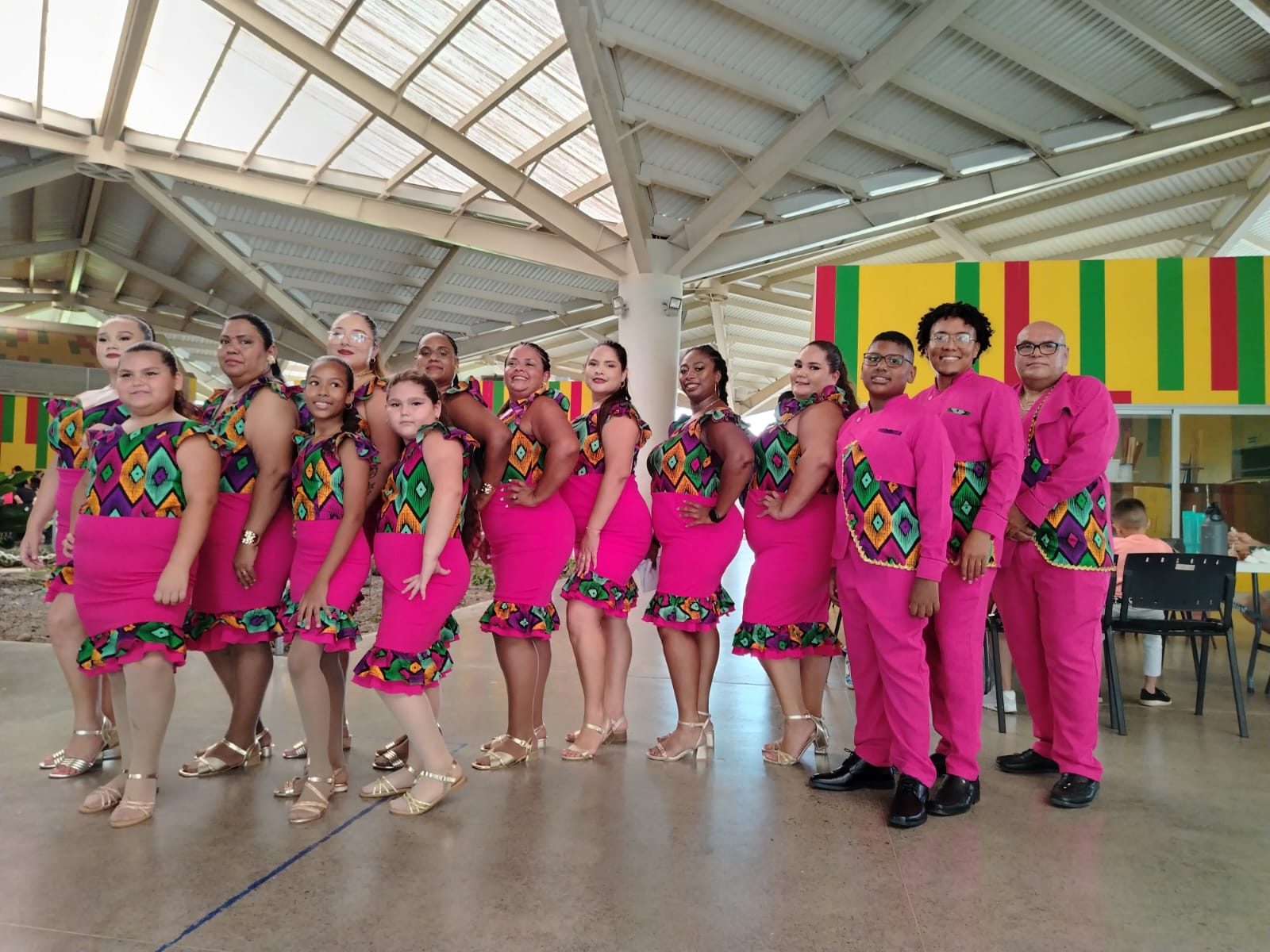 Grupo de personas posando con vestimentas afrocaribeñas color fucsia.