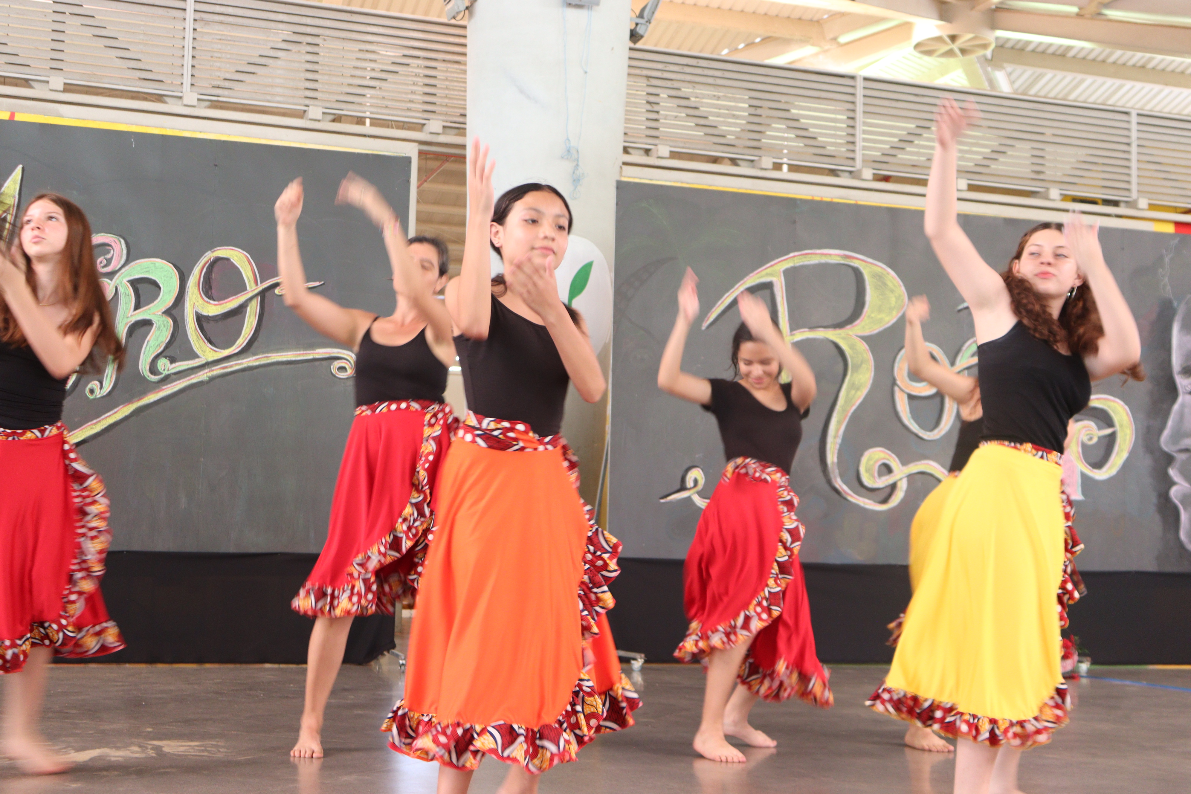 Jóvenes bailando con las manos extendias hacia arriba, viste enaguas de colores