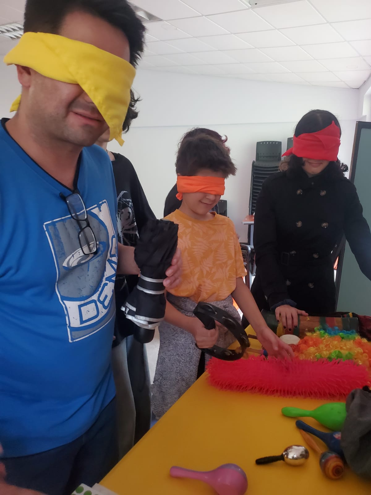 Personas con los ojos vendados tocando diferentes objetos en una mesa