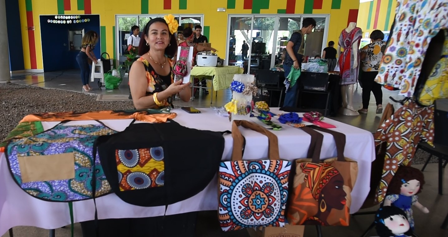 Mujer mirando, detrás de una mesa con bolsos y delantales
