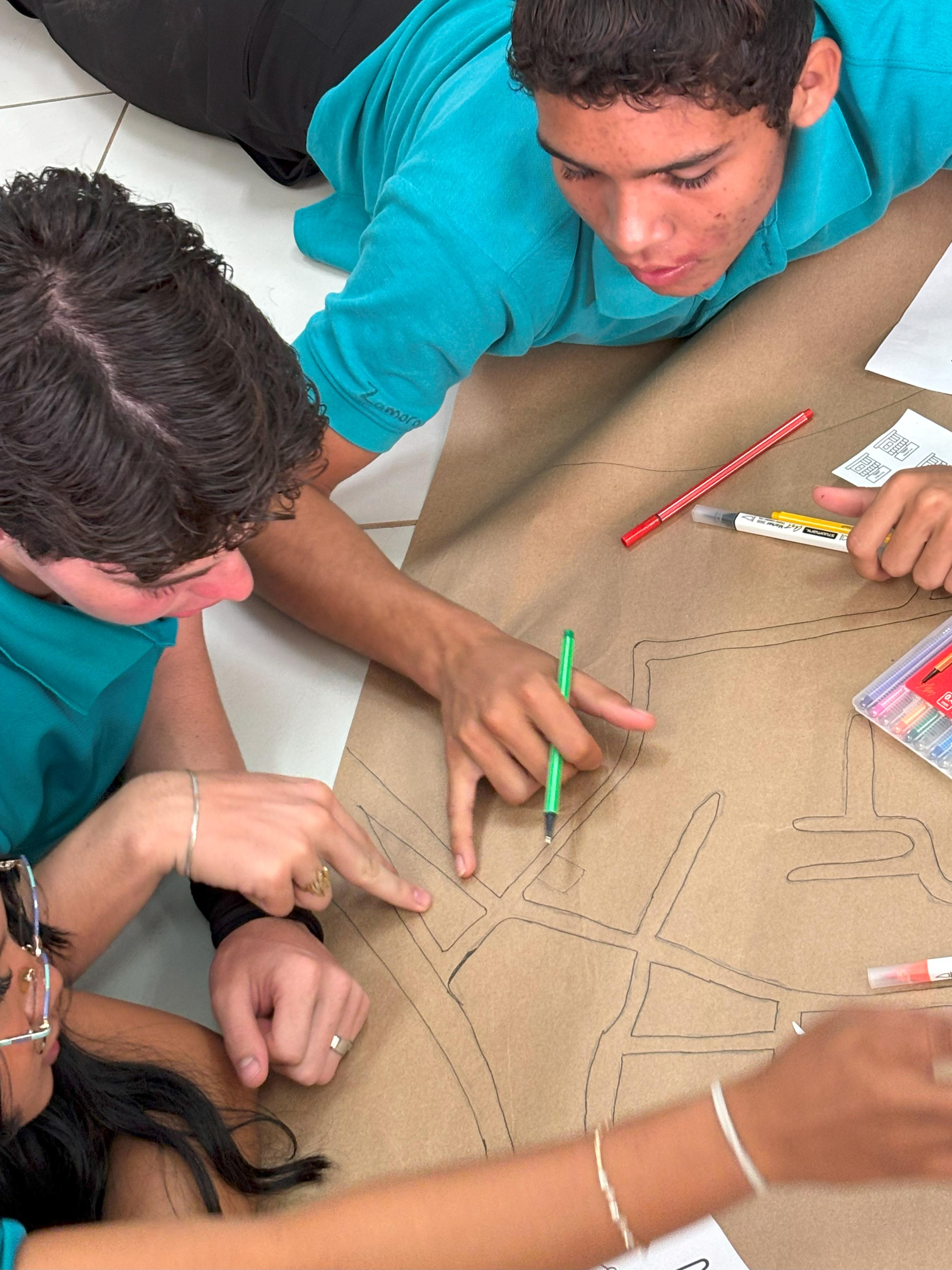 Jóvenes en el piso dibujando sobre un papelografo