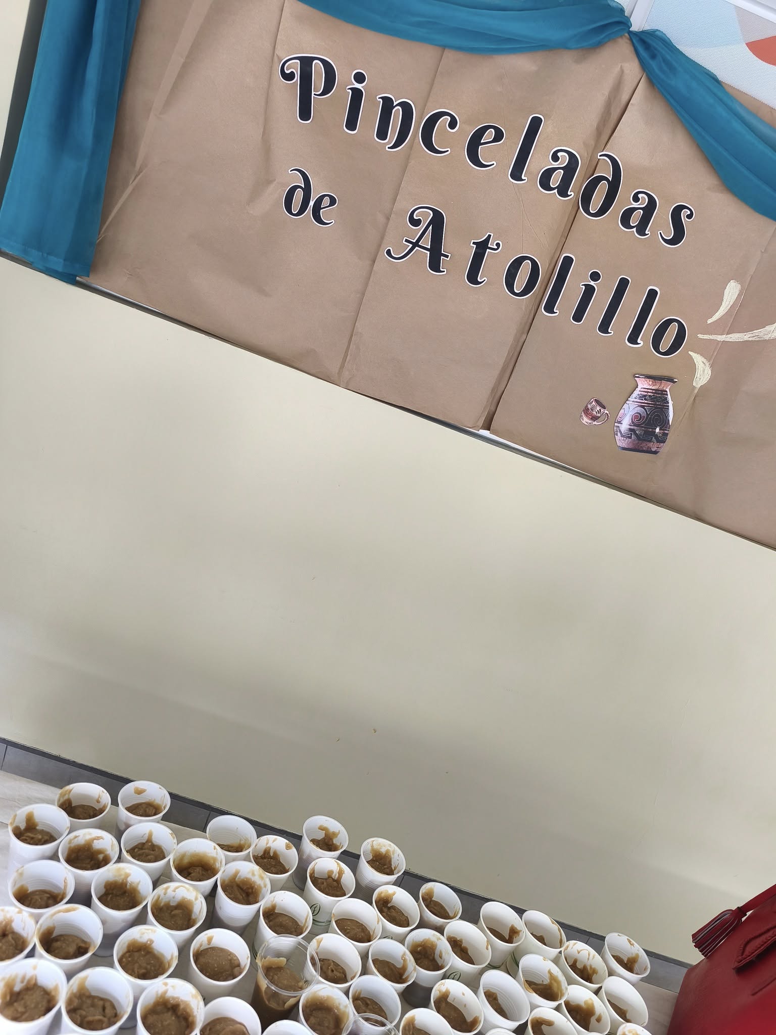 Vasos plasticos con atol, y arriba un letrero que dice Pinceladas de Atolillo