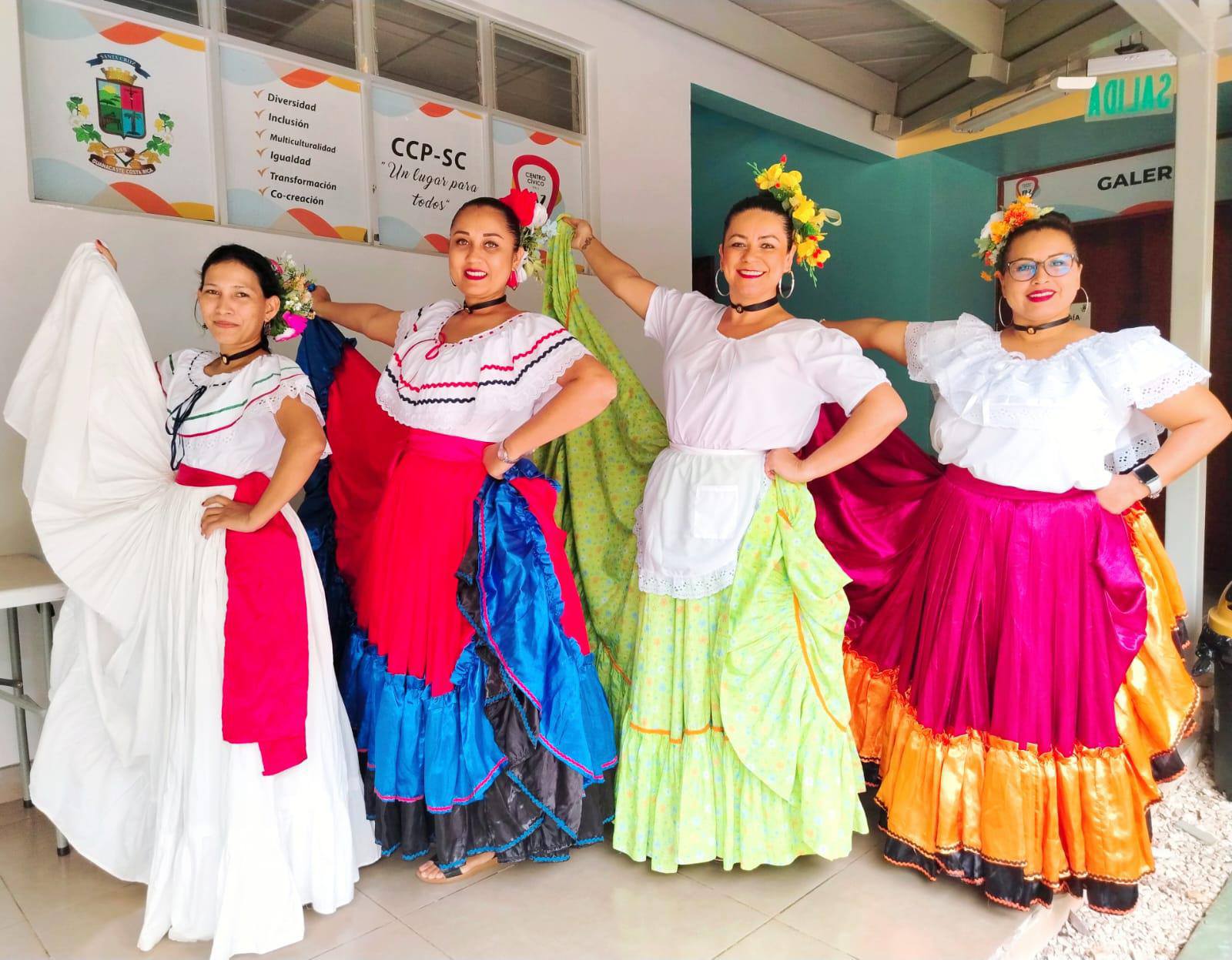 Mujeres levantando su enagua tipica y sonriendo.