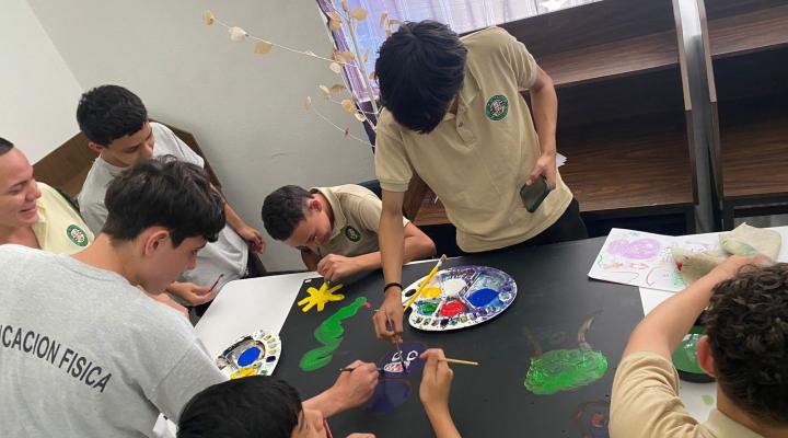 Jóvenes pintando sobre una cartulina negra