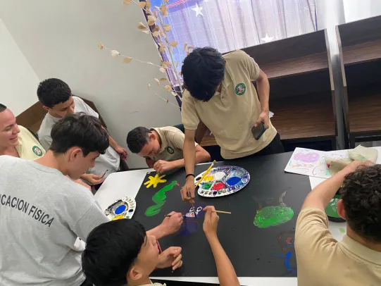 Jóvenes pintando sobre una cartulina negra