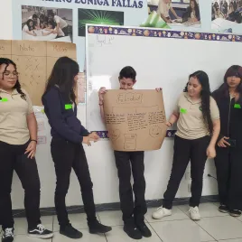 Jovenes exponiedo un papelografo que dice Felicidad