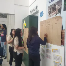 Joven escribiendo en un papelografo sobre una pared