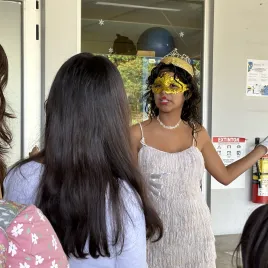 Mujer joven con máscara dorada, otras mujeres de espaldas