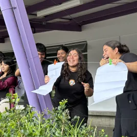 Mujeres jóvenes colgando unos papeles en una cuerda