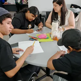 jovenes sentados en una mesa dibujando