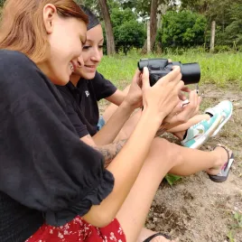 Dos mujeres sentadas en el suelo viendo una cámara