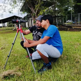 Dos hombres viendo una cámara instalada en un trípode