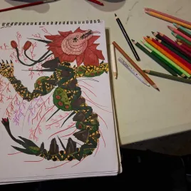 Dibujo de una flor mutante roja con tallo verde, un brazo y una mano, la flor tiene boca y lengua, lapices de color al lado