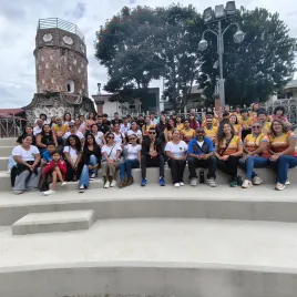 Grupos de personas sentadas en unas gradas, de fondo el Fortín de Heredia