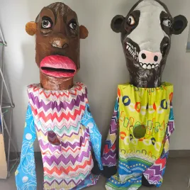 Dos mascaradas con cara de vaca y hombre moreno