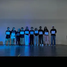 Jovenes sobre escenario sosteniendo un certificado
